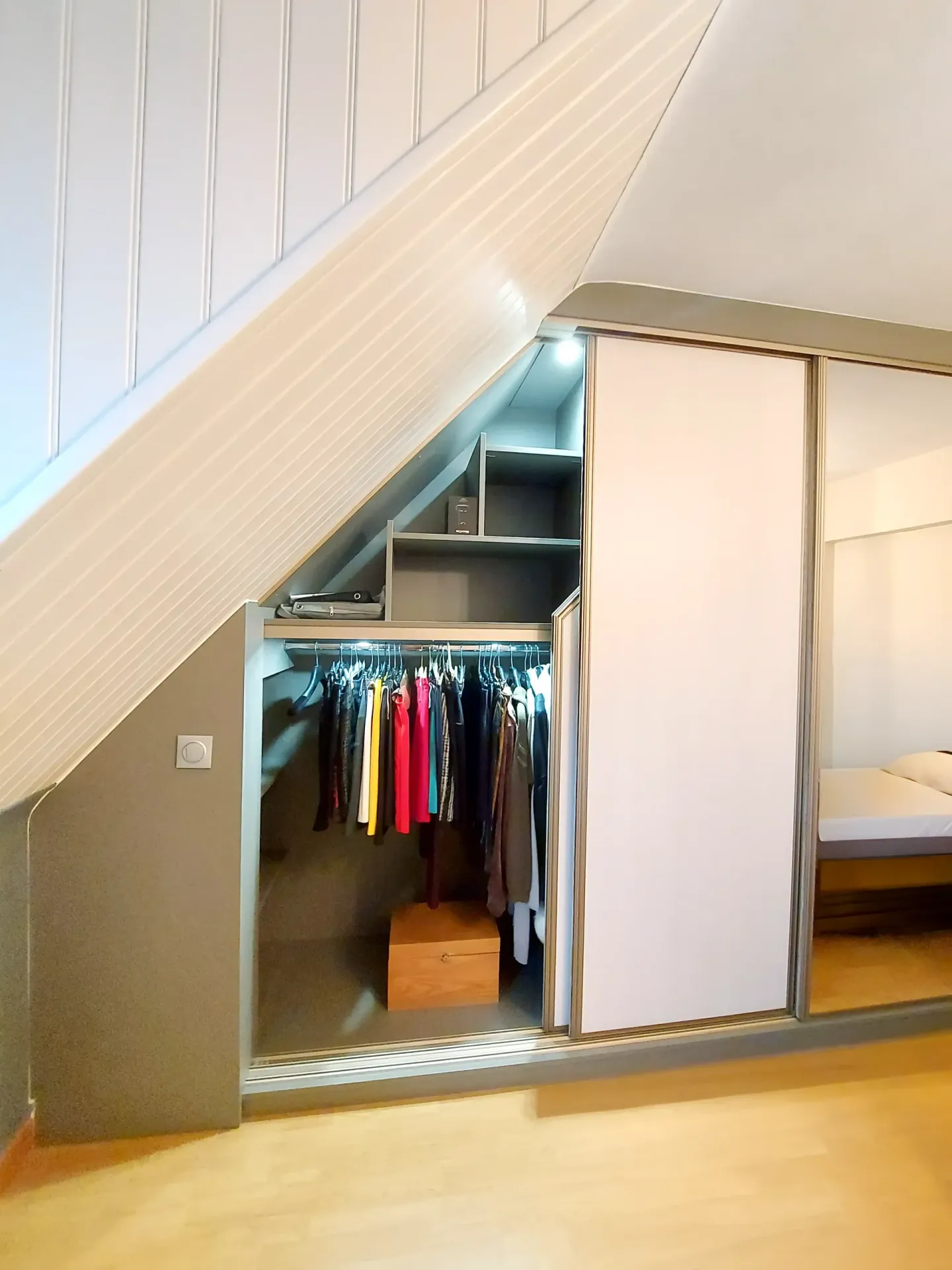 Dressing sous pente ouvert avec portes coulissantes et miroir.